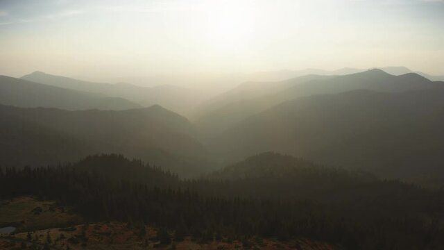 Aerial flight over foggy mountain silhouette ridge canyon. Sunrise sky against highland range and spruce forest. Nature background. Travel destination. Beautiful wild landscape. Cinematic drone flight