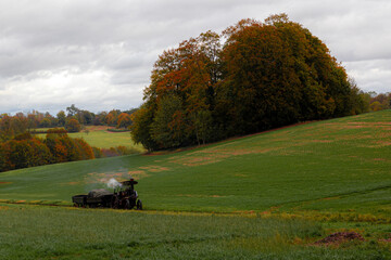 Steam traction engine moving across a grassy hillside.