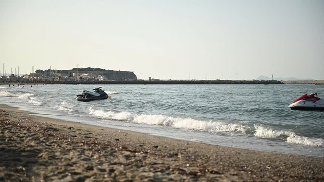 Jet skis float on the waves of the mediterranean sea on the beach at sunset