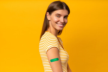 Smiling woman showing shoulder with band aid after Covid 19 vaccine injection