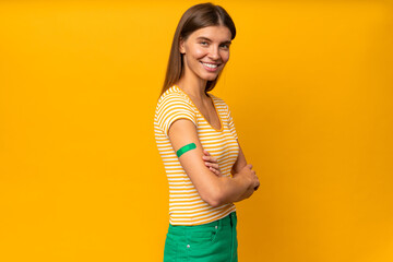 Happy young woman showing her arm with band aid after coronavirus vaccine injection