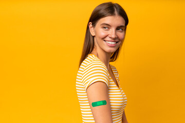Happy woman showing her arm with band aid after coronavirus vaccine injection - obrazy, fototapety, plakaty