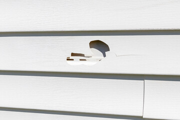 hail damage to vinyl siding on house. Storm damage, home repair and insurance claim concept