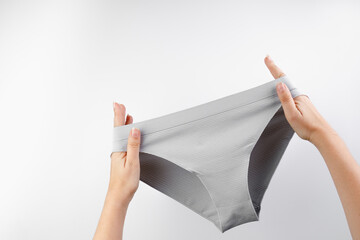 Women's panties isolated on white background. The girl holds panties in her hands. Advertising of...