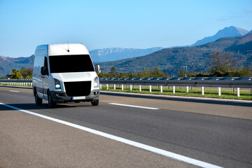 White modern delivery small shipment cargo courier van moving fast on motorway road to city urban suburb.  © Bojan