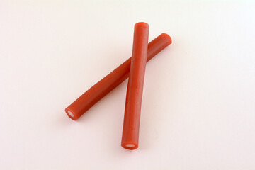 Red licorice and citrus sherbet candy tubes on pink background