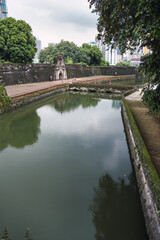 Fototapeta na wymiar Vertical photograph of a water channel before a fortress on a cloudy day. Fort Santiago. Moriones Square. Tourist.