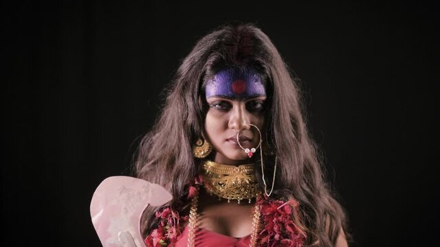 Live Indian Goddess Kali opens her eyes and looks at camera, Indian goddess cosplay with long hair and dark background