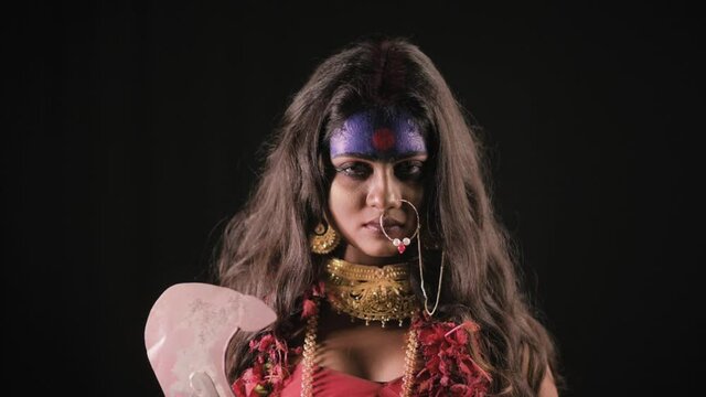 Live Indian Goddess Kali opens her eyes and looks at camera, Indian goddess cosplay with long hair and dark background in studio