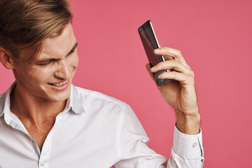 Fototapeta premium handsome man in a white shirt talking on the phone pink background
