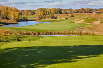 Golf course perfectly manicured on a beautiful fall day with green grass and blue water