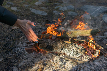 A woman's hand warming up near a campfire.