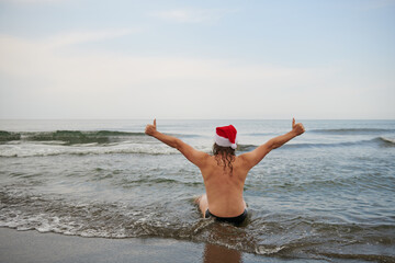 a man wearing a santa claus hat at the sea