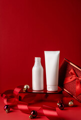 White bottles cosmetic products on red podium and on red background. Christmas sale of beauty...