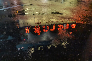 Blurred view of Scala movie theatre at night reflected in water puddle between rain. Thailand.
