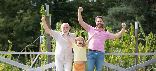 Excited family together with three different generations ages grandfather father and amazed son in spring garden.