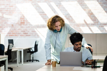 Young multiracial coworkers look at laptop together brainstorming ideas for business. Copy space.