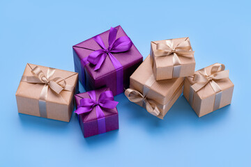 Gift boxes in elegant packaging with ribbons and bows. Blue background, copy space.