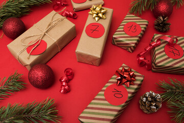 Boxes in kraft paper for the Advent calendar on a red background, Christmas gifts with the dates of...