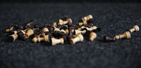 Scattered chess pieces on a blurred black background.