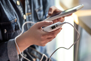 A woman holds a power bank and a phone in her hands.