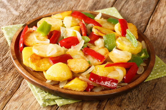 Spanish Patatas a lo Pobre Poor Man&acute;s Potatoes made of sliced potatoes are fried in olive oil with onion and pappers close up in the plate on the table. Horizontal