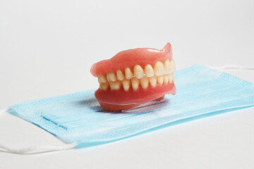 Dental dentures and medical mask on white background