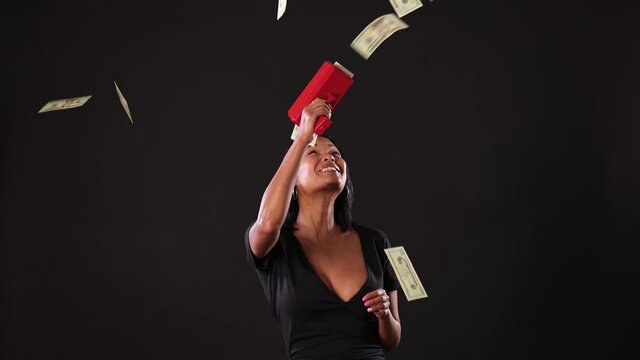 Mixed ethnicity (Asian-African) woman shooting money out of a money gun. Slow Motion.