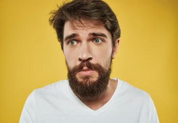 Obraz premium Man in a white t-shirt expressive look discontent yellow background