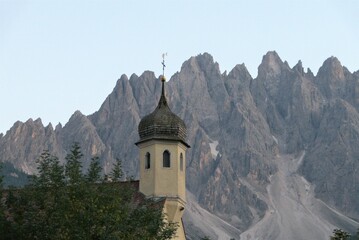 Blick auf den Kirchturm der St. Leopolds Kirche in Innichen im Pustertal, Südtirol, vor massivem Bergpanorama