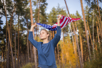 Beautiful girl with American flag. American flag in hands on warm summer forest