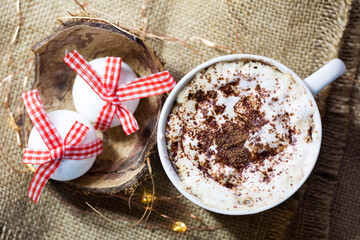 Two white Christmas balls with red ribbons and a cup of coffee, top view