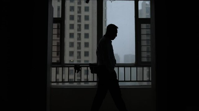 Silhouette of a man wandering in front of the window thinking