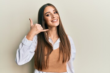 Beautiful brunette young woman wearing casual clothes smiling doing phone gesture with hand and fingers like talking on the telephone. communicating concepts.