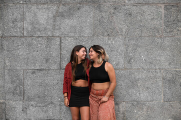Portrait of two girls standing against stone wall