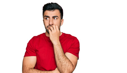 Fototapeta na wymiar Hispanic man with beard wearing casual red t shirt looking stressed and nervous with hands on mouth biting nails. anxiety problem.