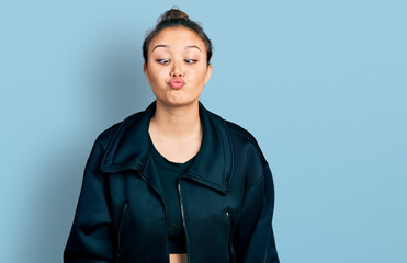 Young hispanic girl wearing sportswear making fish face with lips, crazy and comical gesture. funny expression.