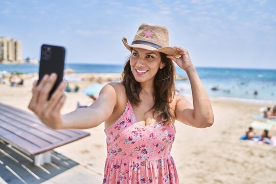 Brunette woman enjoying a summer day at the beach taking a selfie picture with smartphone