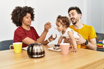 Couple and daughter having breakfast sitting on table at home
