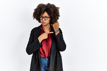 African american woman with afro hair wearing business jacket and glasses in hurry pointing to...
