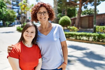 Mature mother and down syndorme daughter smiling happy and friendly outdoors
