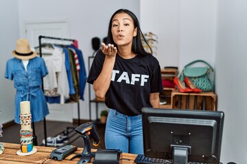 Young hispanic woman working as staff at retail boutique looking at the camera blowing a kiss with hand on air being lovely and sexy. love expression.