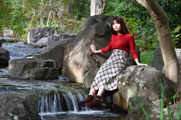 Fototapeta na wymiar 水辺の岩に座る女性