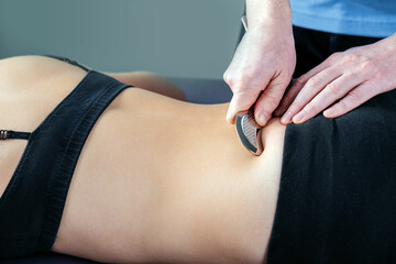 Physical therapist fixing sacroiliac joint pain with IASTM tool
