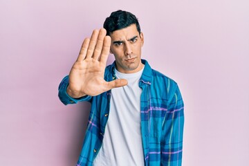 Handsome hispanic man wearing casual clothes doing stop sing with palm of the hand. warning...