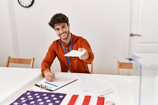 Young hispanic man smiling confident holding vote and writing on checklist at electoral college