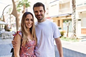 Fototapeta premium Young hispanic couple hugging in love at the city. Girlfriend and boyfriend together in love walking on the street