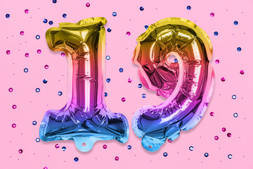Rainbow foil balloon number, digit nineteen on a pink background with sequins. Birthday greeting card with inscription 19. Top view. Numerical digit. Celebration event, template.