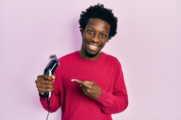 Young african american man holding razor smiling happy pointing with hand and finger