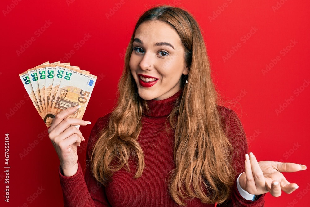 Poster Young blonde woman holding euro banknotes celebrating achievement with happy smile and winner expression with raised hand